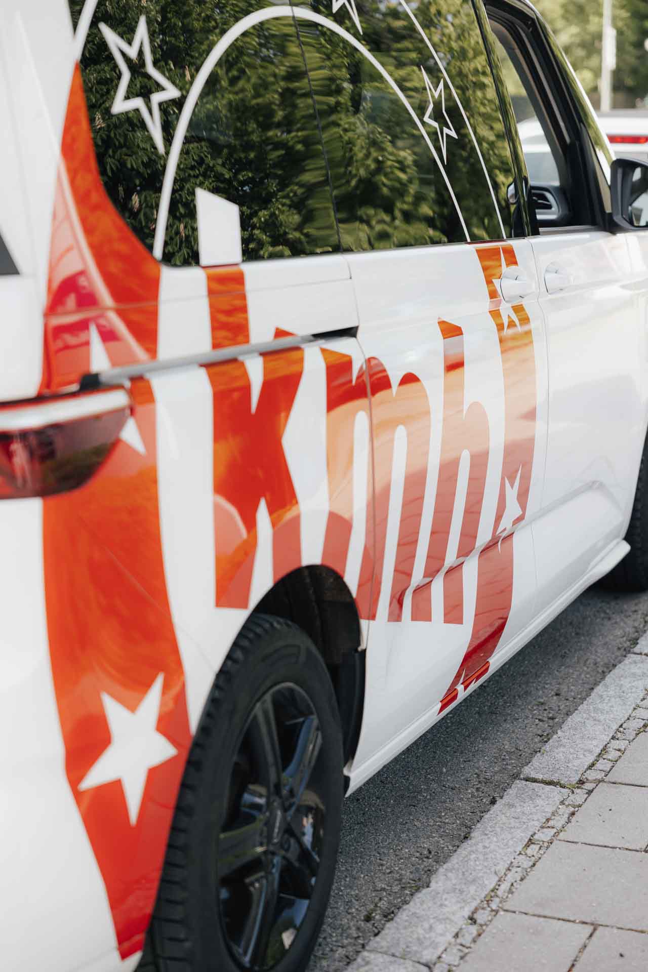 Detailansicht des kmh Logos am Heck eines Fahrschulfahrzeugs.