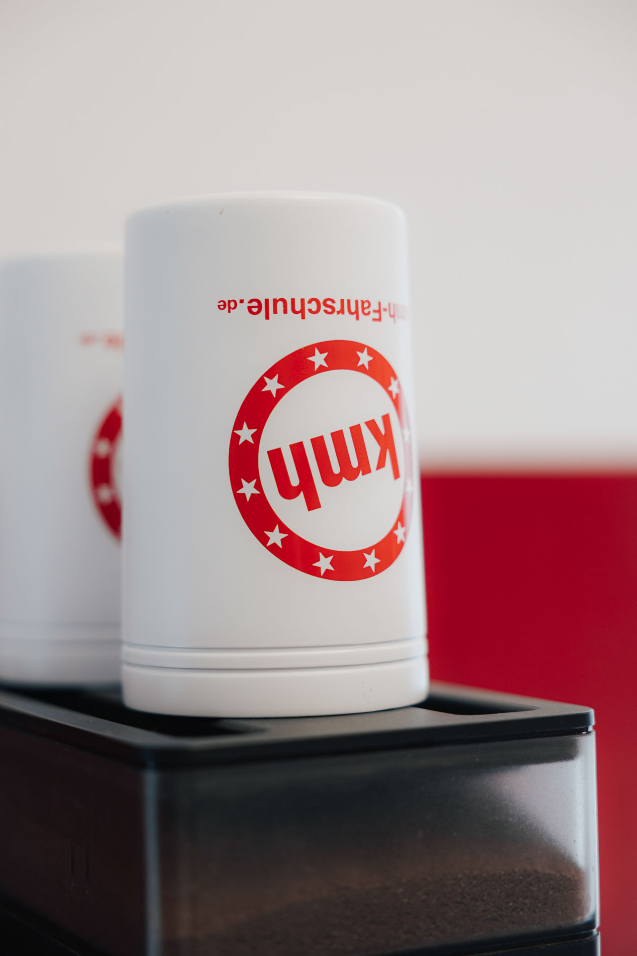 Umgedrehte Kaffeebecher mit kmh-Logo auf unserer Kaffeemaschine.