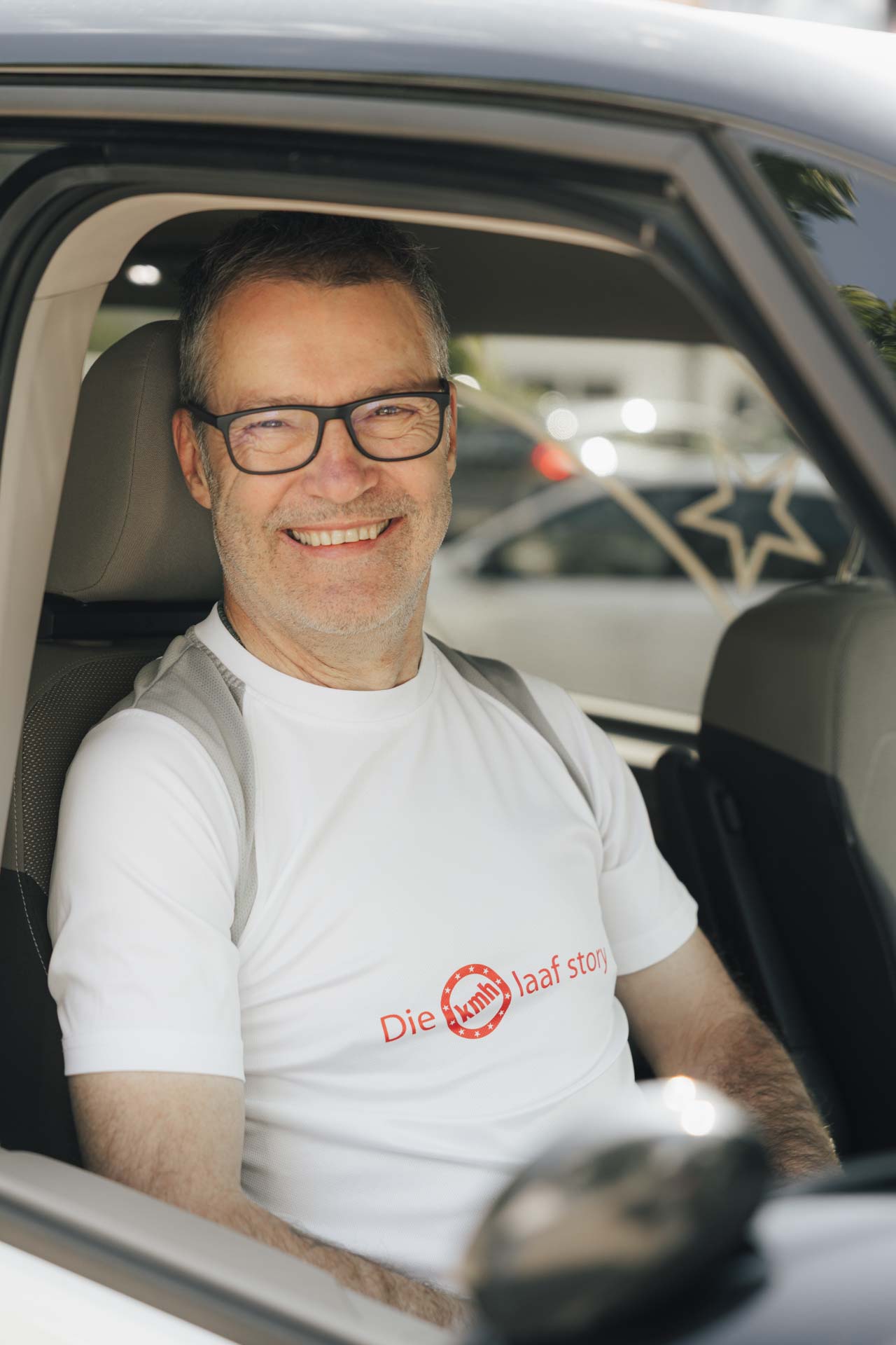 Fahrlehrer Bernhard von Fahrschule kmh, freundlich lächelnd, durch das Beifahrerfenster fotografiert.