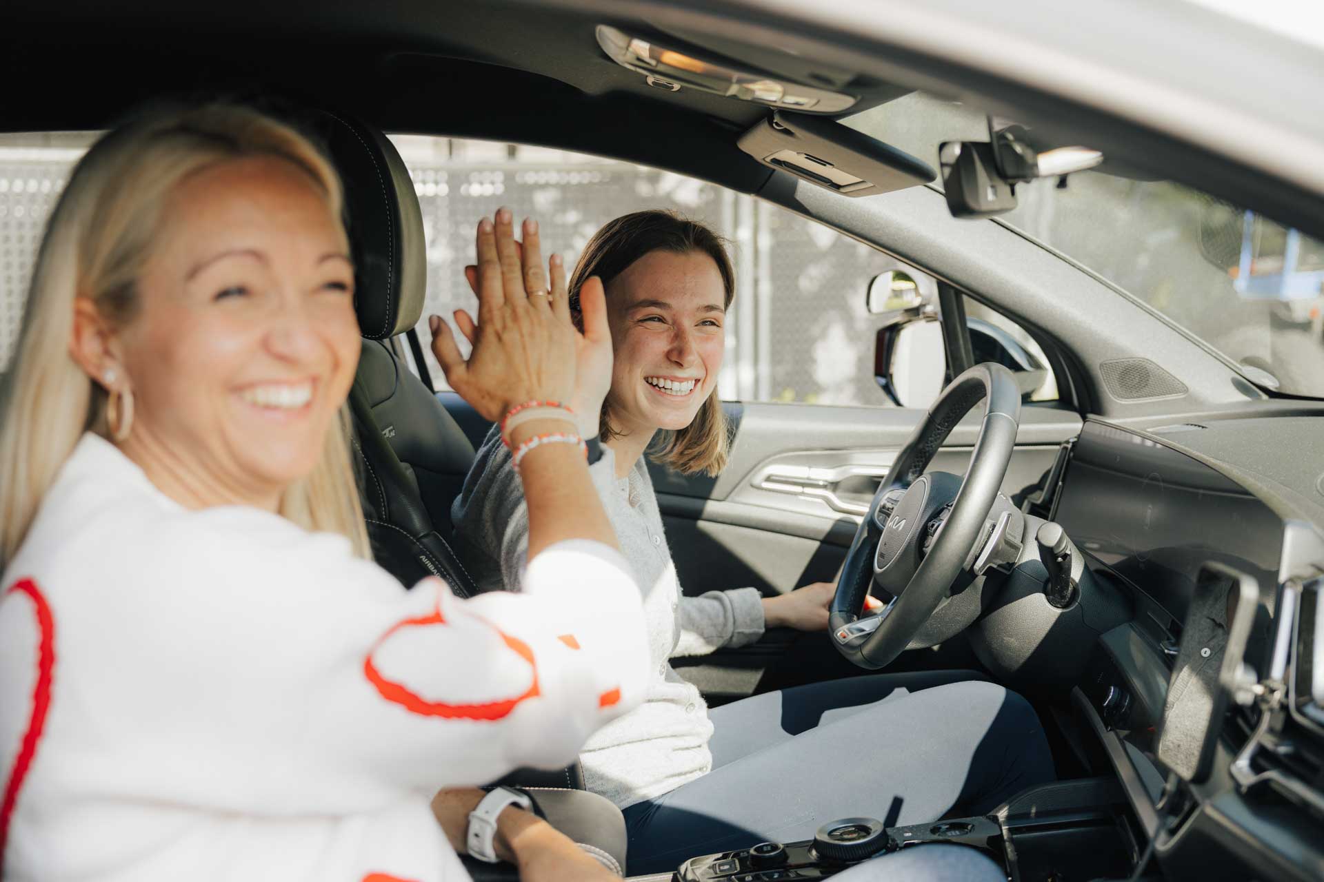 Martina von der fahrschule kmh im Auto beim Unterricht, gibt High Five mit Schülerin.