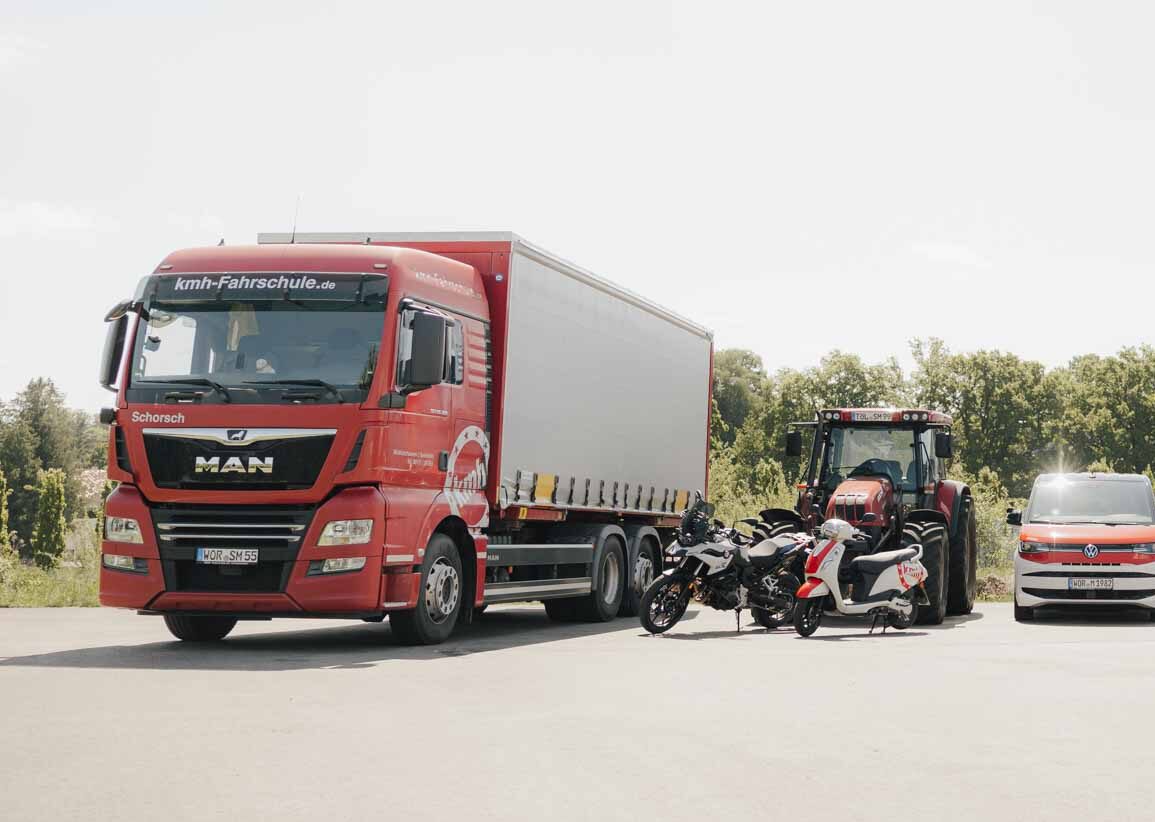 Ausbildungsfahrzeuge der Fahrschule kmh: Ein LKW, Motorrad, Roller, Traktor und VW Bus nebeneinander geparkt.